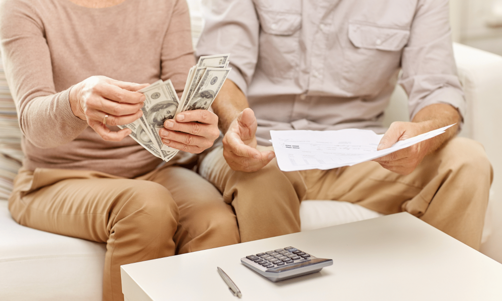 older man and woman discussing their finances while counting the extra money they have after adopting a Minimalist lifestyle.